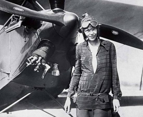 Amelia Earhart standing outside of her airplane after landing it. 