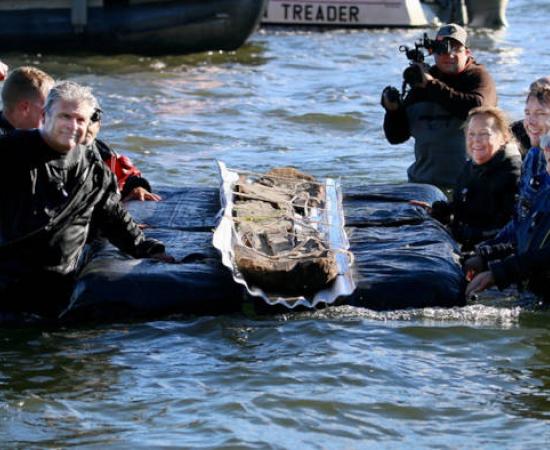 Volunteers and researhcers removing a 3,000 year old canoe from a lake.
